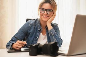 fotógrafa de mulher feliz com uma câmera sem espelho no local de trabalho foto