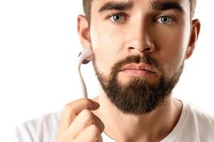 homem bonito usando meso roller para melhorar o crescimento da barba foto