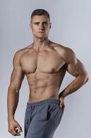 fisiculturista mostrando seu corpo musculoso contra um fundo cinza foto