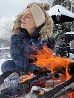 jovem se aquecendo na fogueira durante o dia frio de inverno foto