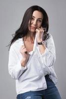 bela modelo de moda de meia idade vestindo jeans e camisa branca em um estúdio de fotografia foto