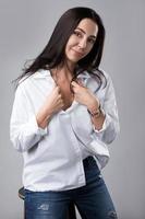 bela modelo de moda de meia idade vestindo jeans e camisa branca em um estúdio de fotografia foto