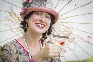 menina vestida de 1920 com guarda-sol e copo de retrato de vinho foto