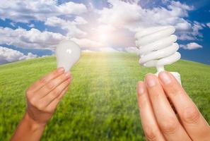 mãos femininas segurando lâmpadas comuns e de economia de energia foto