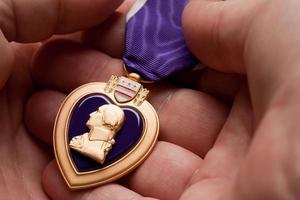 homem segurando medalha de guerra de coração roxo foto