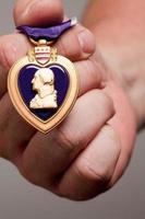 homem segurando medalha de guerra de coração roxo foto