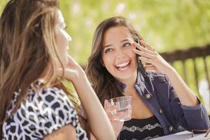 meninas de raça mista falando em seus telefones celulares foto