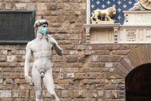 a estátua de david na piazza della signoria, na itália, usando máscara protetora médica azul foto