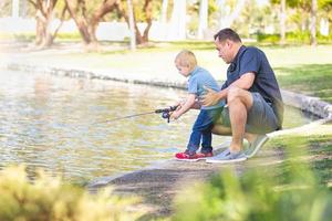 jovem caucasiano pai e filho se divertindo pescando no lago foto