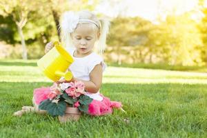 menina bonitinha jogando jardineiro com suas ferramentas e vaso de flores. foto