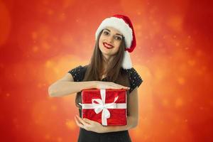 menina elegante com chapéu de Papai Noel com presente vermelho foto