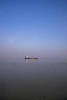 paisagem de um pequeno navio de carga contra um céu azul no rio padma bangladesh foto