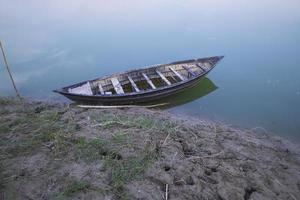 paisagem de um barco de madeira na margem do rio padma em bangladesh foto