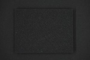 uma esponja preta sobre um fundo preto. borracha de espuma preta em pano preto. o quadrado preto da junta. foto