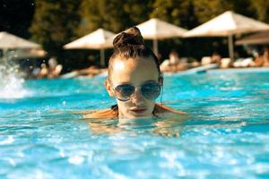 garota sexy em óculos de sol na piscina foto