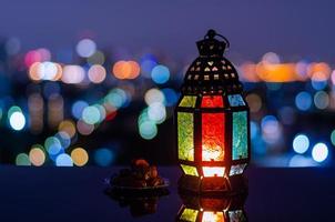 lanterna e pequeno prato de frutas tâmaras com fundo claro de bokeh da cidade para a festa muçulmana do mês sagrado do ramadã kareem. foto