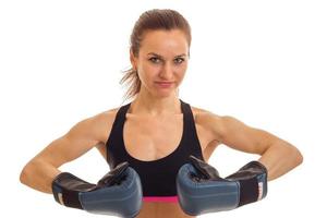 uma jovem lutando no topo olha para a câmera e dá as mãos pera está em luvas de boxe foto