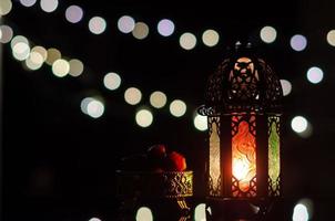 lanterna e tâmaras frutas com luz de bokeh em fundo escuro para a festa muçulmana do mês sagrado do ramadã kareem. foto