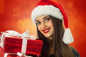 menina de chapéu de Papai Noel com caixa de presente vermelha foto