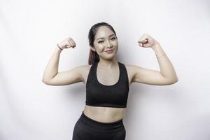mulher esportiva asiática animada vestindo roupas esportivas mostrando gesto forte levantando os braços e músculos sorrindo com orgulho foto