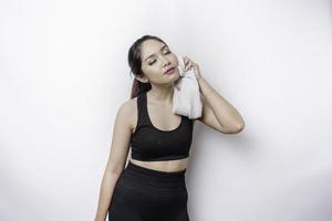 mulher asiática esportiva posando com uma toalha no ombro, cansada após o treino foto