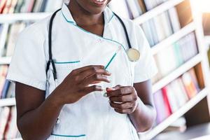 enfermeira de medicação vestindo jaleco branco prepara uma agulha ou injeção para uma injeção. médica negra com frasco e seringa no hospital. dia de vacinação foto