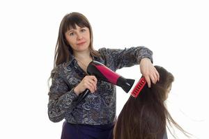 mãe faz um penteado para sua filhinha com secador de cabelo foto