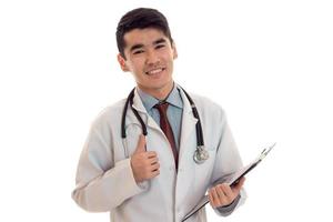 médico jovem bonito posando e sorrindo de uniforme isolado no fundo branco no estúdio foto