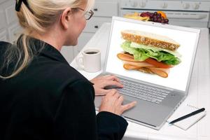 mulher na cozinha usando laptop - comida e receitas foto