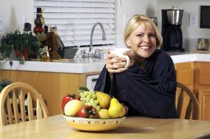 mulher na cozinha com uma xícara de café foto