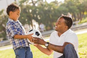 pai entrega nova bola de futebol para filho mestiço foto