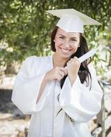 graduando-se menina de raça mista em boné e vestido com diploma foto