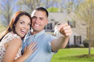 casal militar com chaves de casa na frente da nova casa foto