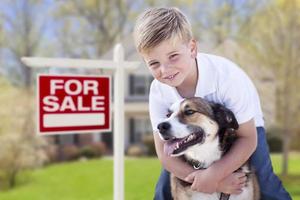 menino e seu cachorro na frente de casa e sinal de venda foto