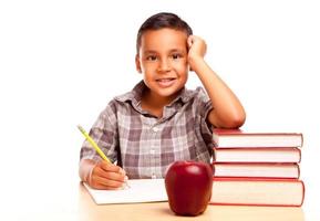 adorável menino hispânico com livros, maçã, lápis e papel foto