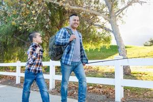 raça mista pai e filho caminhando ao ar livre com varas de pesca foto