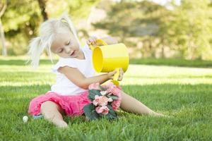 menina bonitinha jogando jardineiro com suas ferramentas e vaso de flores. foto