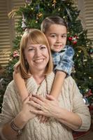 mãe e filho mestiço se abraçam perto da árvore de natal foto