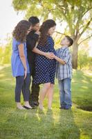 família hispânica atraente feliz com sua mãe grávida ao ar livre foto