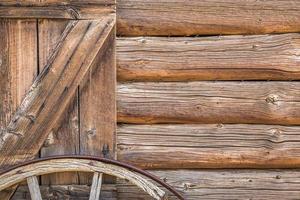 resumo da parede da cabana de madeira antiga vintage e roda de carroça. foto