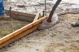 trabalhador da construção civil colocando cimento de convés molhado em moldura de madeira foto