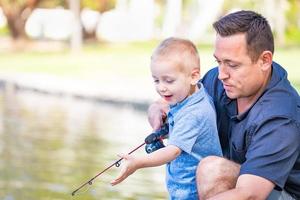 jovem caucasiano pai e filho se divertindo pescando no lago foto