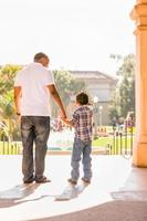 feliz pai afro-americano e filho mestiço caminhando no parque foto