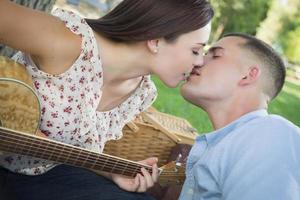 casal de raça mista com beijo de guitarra no parque foto