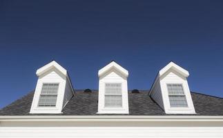 telhado da casa e janelas contra o céu azul profundo foto