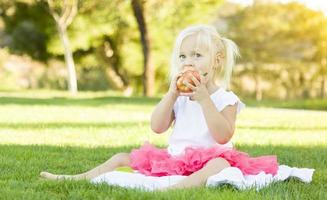 menina na grama comendo maçã saudável foto