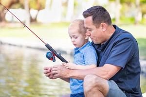 jovem caucasiano pai e filho se divertindo pescando no lago foto