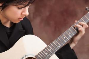 atraente garota étnica toca guitarra foto