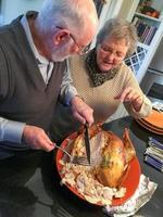 casal adulto sênior cortando o peru de férias juntos foto