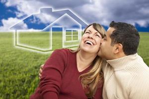 casal feliz sentado no campo de grama com casa fantasma atrás foto